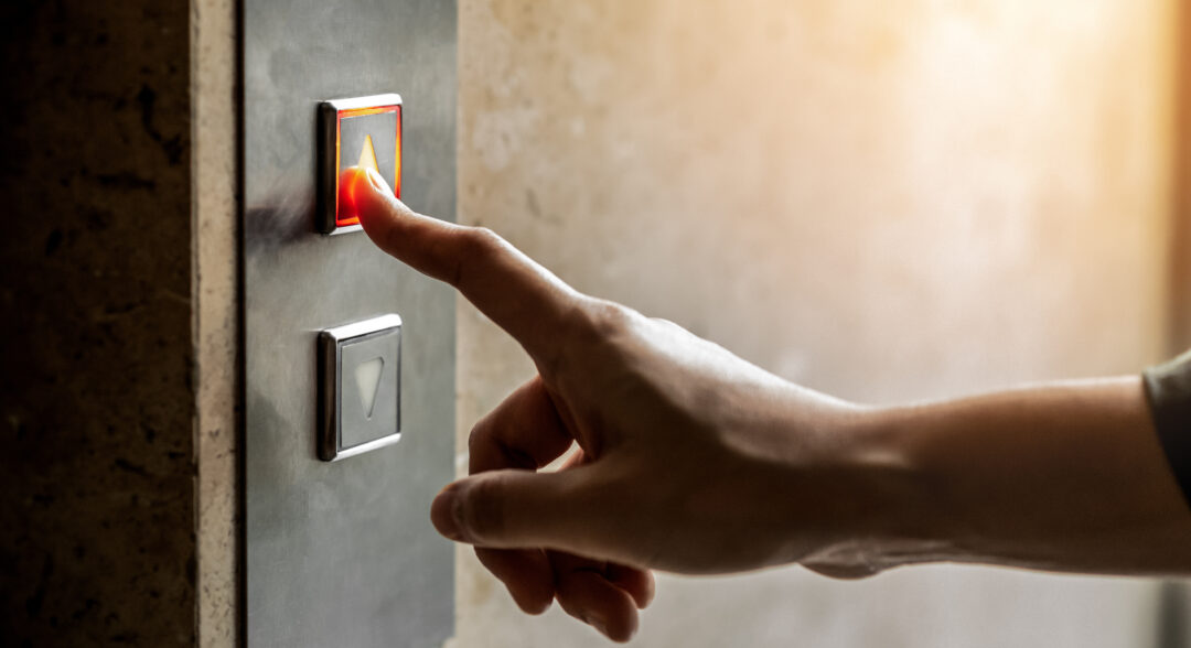 Női uj megnyomja a lift fel gombot felső szintre.
