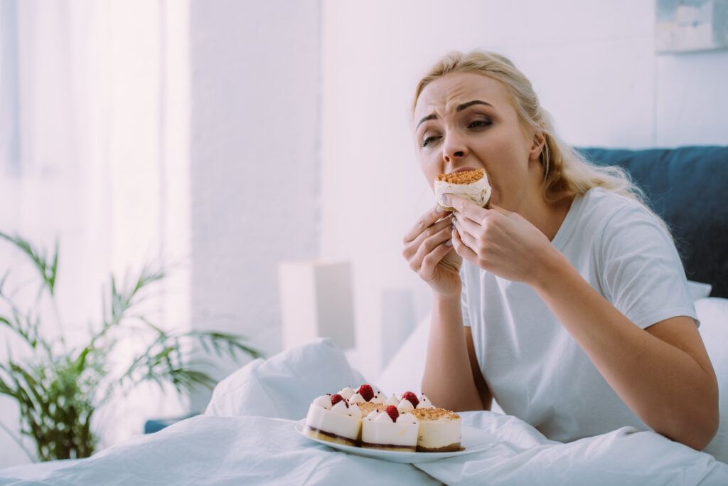 Depresszív nő tortát eszik az ágyban