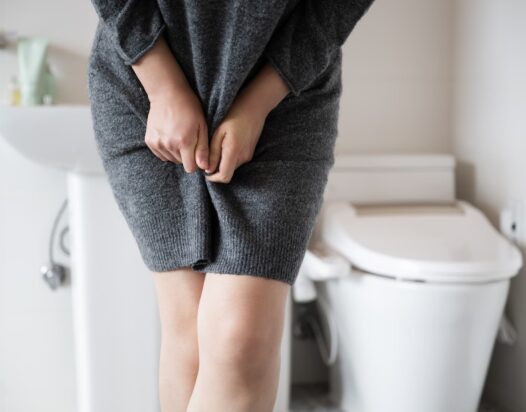 vizelettartási zavarokkal küzdő nő a wc előtt
