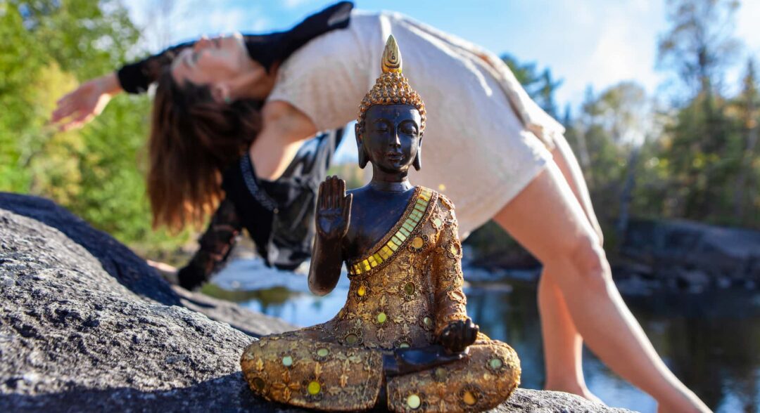 buddhista szobor mögött jógázó nő