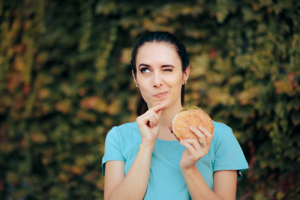 Fiatal nő azon gondolkodik, megegye-e a hamburgert