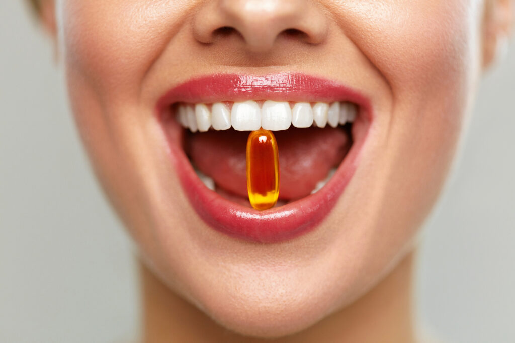 Gyönyörű nő szája tablettával a fogakban. Lány, aki vitaminokat szed