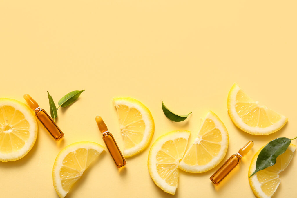 C- vitamin ampulla és citromszeletek citromsárga háttér előtt.