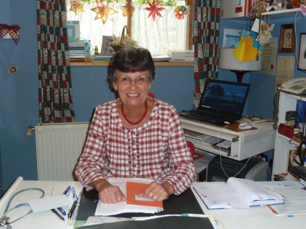 Dr. Molnár Mariann homeopata gyerekorvos az íróasztalánál ül.