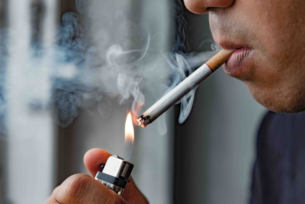 Dohányzó férfi épp rágyújt egy szál cigarettára.