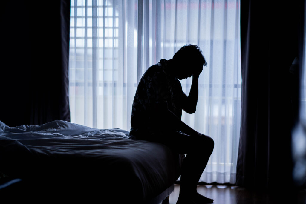 Depressziós férfi ül az ágyon.
