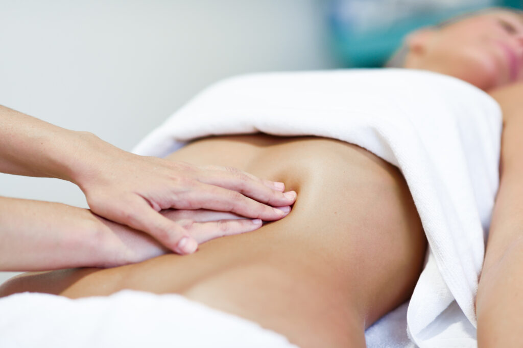 Oszteopátiás kezelés. Egy nő bordája alatt a terapeuta kezével mély nyomást végez. 