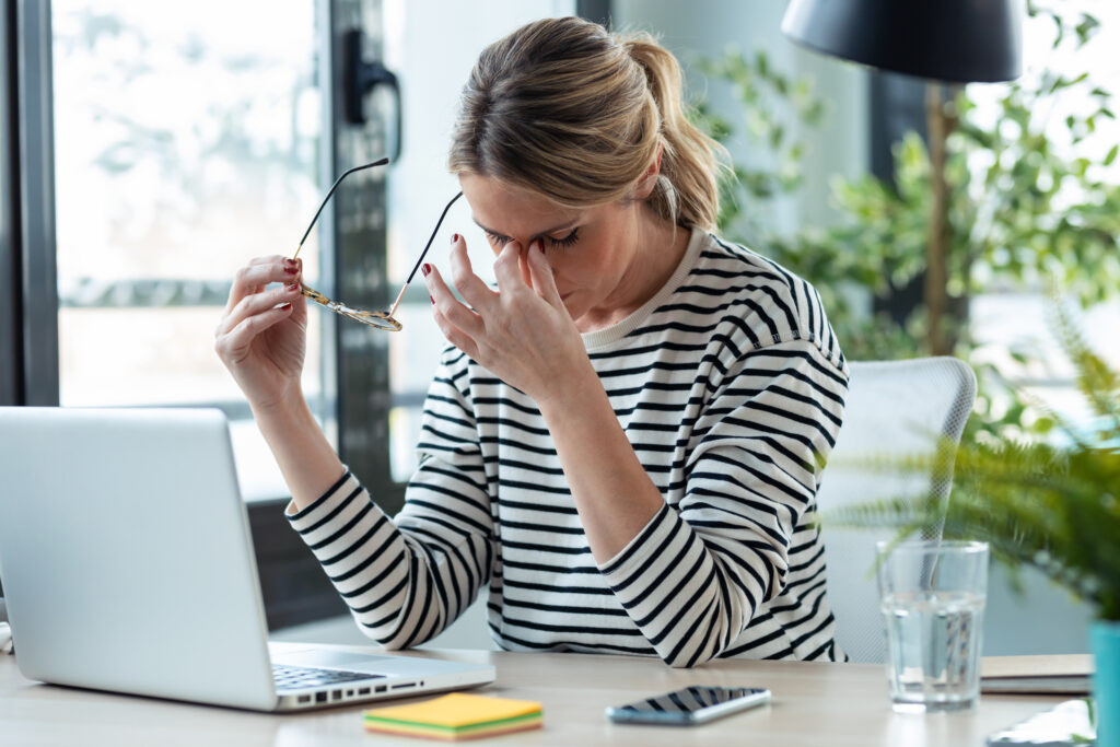 Stresszelt nő fogja a fejét az irodában a számítógép előtt.