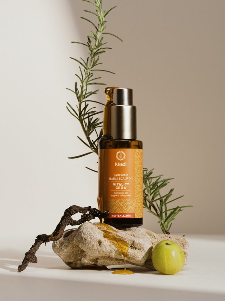 Khadi Vitality Grow ayurvédikus hajolaj tubusban, háttérben egy rozmaring ág.